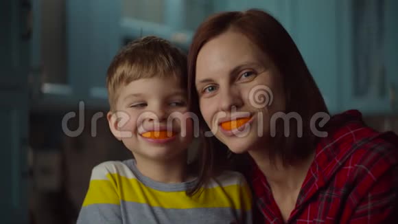 有趣的一家人在橘子皮微笑的女人和学龄前儿童带着橘子水果视频的预览图