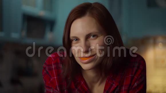 接近30多岁的年轻女人在嘴里玩橘子皮微笑的雌性嘴里有橘子水果橙色视频的预览图