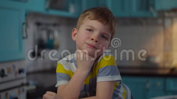 忧郁的金发学龄前男孩看镜头的肖像孩子们在家里的桌子上一个接一个的想着男孩视频的预览图