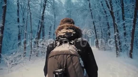 有抱负的摄影师背包客走在傍晚森林雪花飘落视频的预览图
