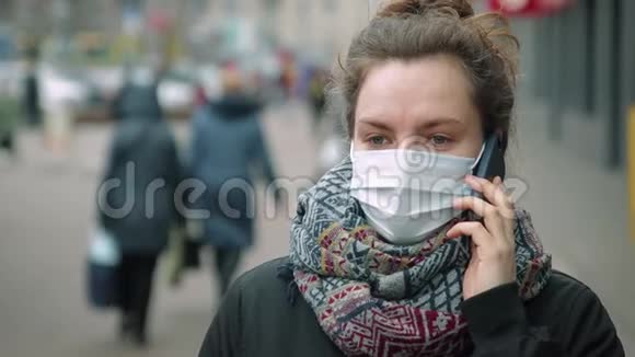 在繁忙的街道上戴着防护面具打电话的妇女视频的预览图