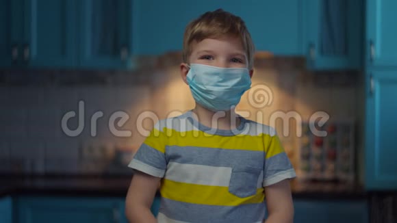 戴着医用面罩的金发男孩用红外温度计对着摄像机测量体温戴着医用口罩的孩子视频的预览图