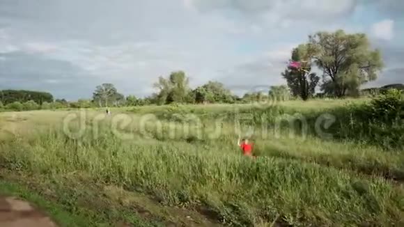 一个小男孩带着风筝跑过田野孩子在大自然中散步视频的预览图