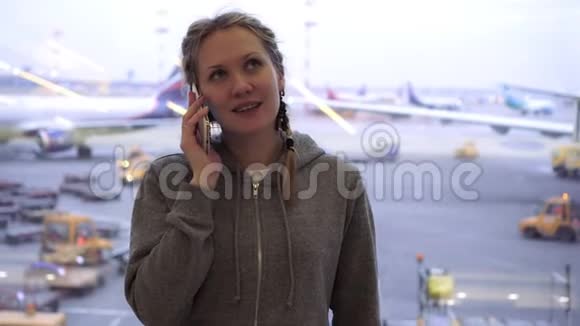 女游客在机场的智能手机上谈论飞机背景视频的预览图