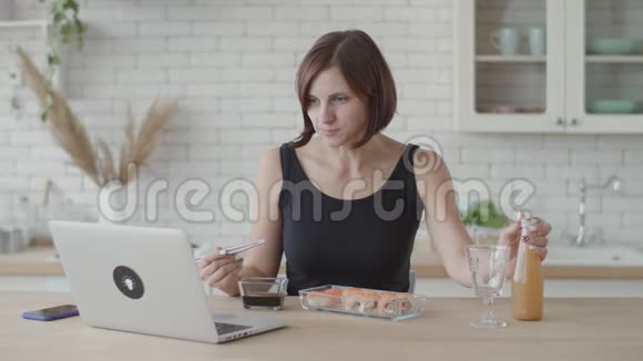 黑衣女子在明亮的厨房里吃寿司欧洲女性在使用日本食物时视频的预览图