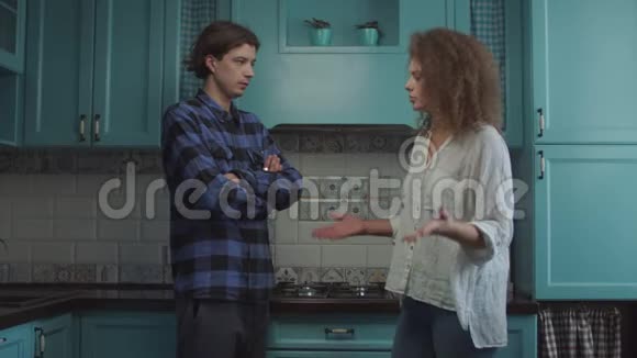 20多岁的年轻夫妇站在家里的蓝色厨房里吵架女朋友尖叫着指责男朋友然后走了视频的预览图