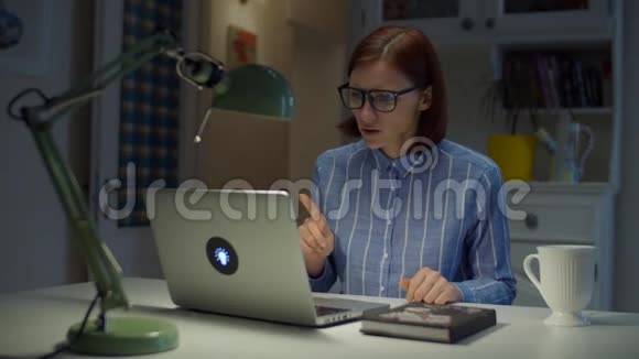 30多岁的年轻女教师戴着眼镜情绪激动地用拇指向下看着家里的笔记本电脑在线教育视频的预览图