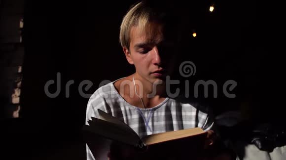 一个年轻人读一本书然后看着窗外深思熟虑的样子有趣的书舒适的气氛视频的预览图