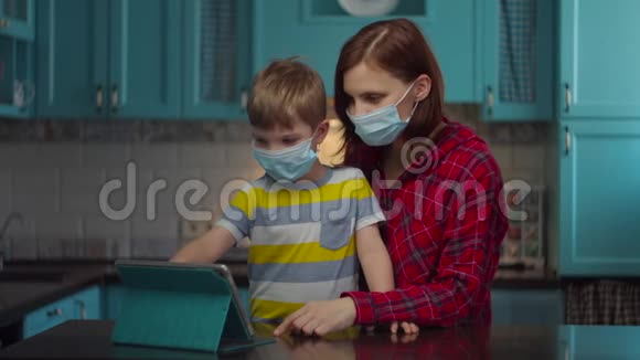 30多岁的母亲和男孩戴着医疗面具用平板电脑与亲戚们在线交谈挥手致意家庭视频的预览图