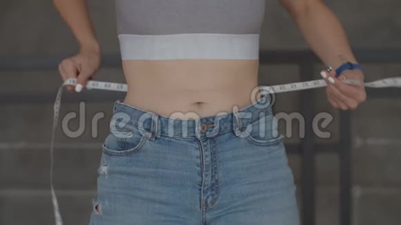 因减肥用厘米卷尺测量年轻女子腹部的特写镜头身材苗条的大号女人视频的预览图