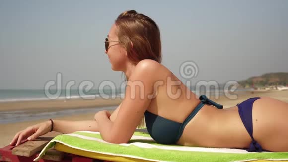 海滩上美丽的年轻女子在甲板椅上晒太阳视频的预览图