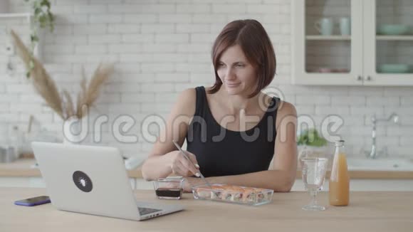 黑衣女子在明亮的厨房里吃寿司欧洲女性在使用日本食物时视频的预览图
