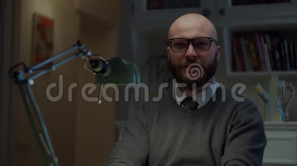 戴眼镜的30多岁大胡子的男人有感情地说话并表现出五根手指在家看着相机在线教育程序视频的预览图