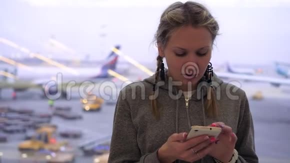 一位女士在机场使用智能手机背景是飞机视频的预览图