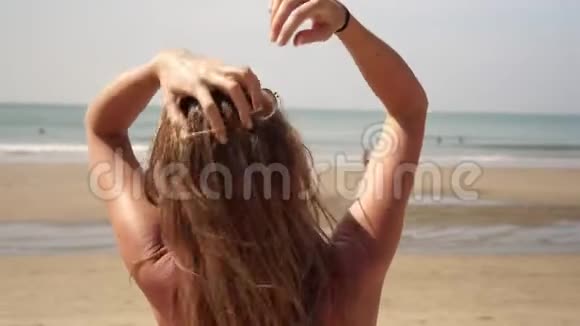 海滩上美丽的女人用她的头发握住她的手视频的预览图