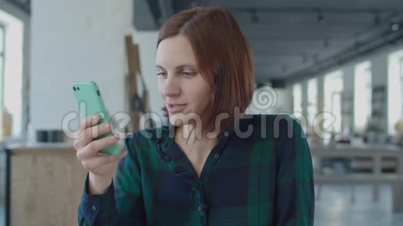 接近30多岁的年轻女职工与手机屏幕交谈坐在大房间的木桌旁视频的预览图