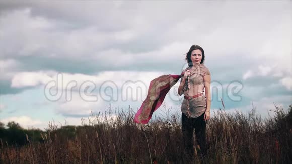 一个女孩站在树叶的田野里吹着风视频的预览图