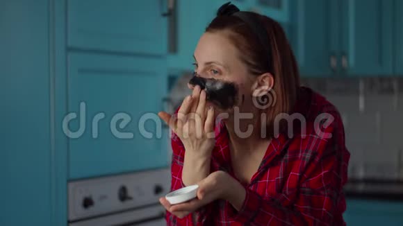 30多岁的年轻女性头上戴着黑色的箍脸上戴着黑色的化妆面具在家穿蓝色衣服的女人视频的预览图