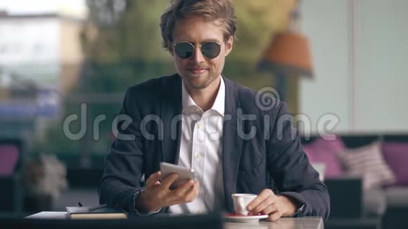 年轻的商人坐在咖啡馆里打电话视频的预览图