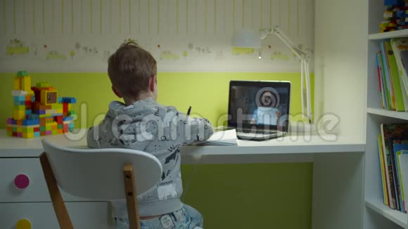 学龄前男孩与女教师在笔记本电脑屏幕上做在线学校作业孩子从书架上拿课本视频的预览图