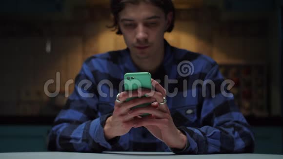 20多岁的年轻人手里拿着手机坐在黑暗中男人手拿着手机视频的预览图