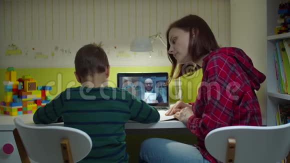 在笔记本电脑屏幕上与男老师在线上课时男生与妈妈一起做作业网上在线视频的预览图