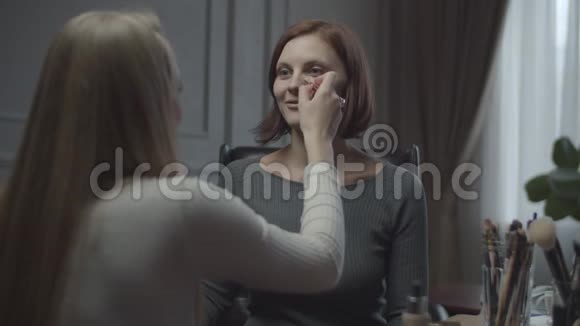 两个女朋友的同事在办公室化妆和大笑女人在工作场所化妆朋友视频的预览图