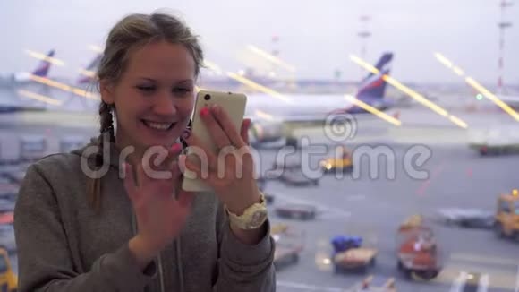 女游客在机场用智能手机打视频电话视频的预览图