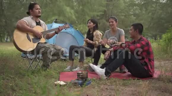 亚洲青少年群体在森林露营玩吉他和唱歌视频的预览图