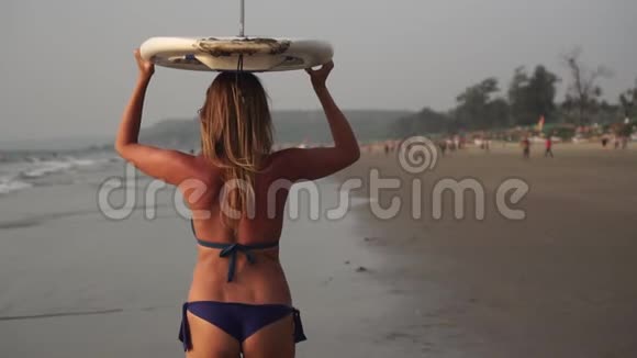 年轻迷人的冲浪女孩穿着比基尼在海滩冲浪视频的预览图