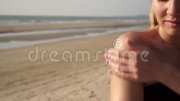 一个穿着泳衣在海滩上的女人把防晒霜涂在皮肤上视频的预览图