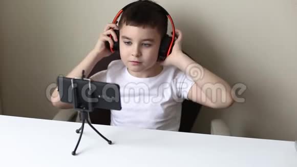 一个男孩用耳机看他的手机视频的预览图