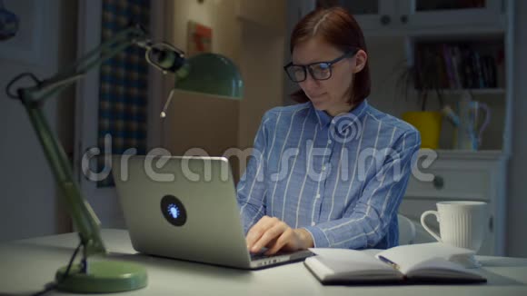 满意的30多岁在家里工作女人在笔记本电脑上打字微笑在线教育过程戴眼镜的女商人视频的预览图
