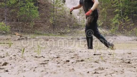一个肮脏的人在泥泞的水坑里行走视频的预览图