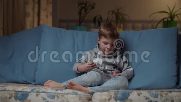 金发的学龄前男孩晚上在舒适的沙发上吃完午饭然后把碗给妈妈小孩吃白饭视频的预览图
