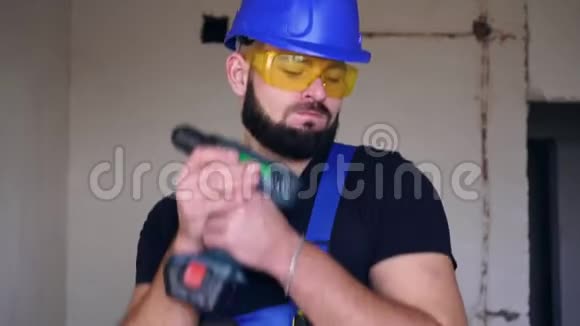 开朗的男性建筑工人正在用电动螺丝刀在房子里跳舞视频的预览图
