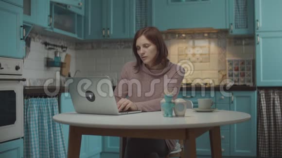 年轻的30多岁的女性厌倦了在家工作关闭笔记本电脑喝杯咖啡女人停下来享受视频的预览图