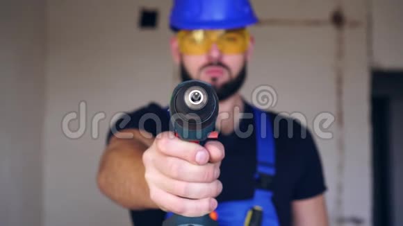 一个男建筑工人拿着一把电动螺丝刀穿制服的男工的肖像视频的预览图