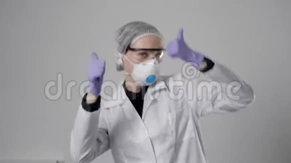 开朗的女医生戴着防护面具戴着帽子戴着眼镜穿着长袍在医院跳舞兴高采烈视频的预览图