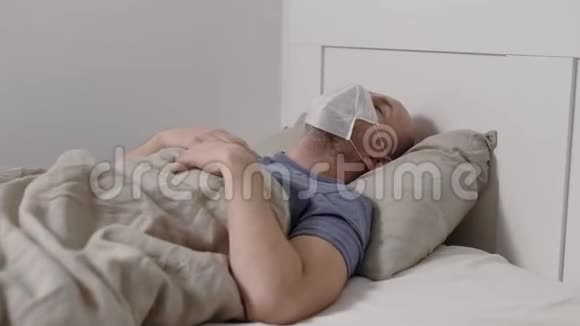男性冠状病毒covid19患者躺在床上在医院房间咳嗽脸上戴着医用口罩视频的预览图