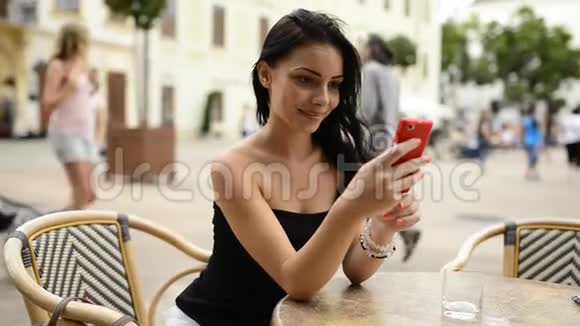 漂亮的女孩在桌子上玩手机视频的预览图