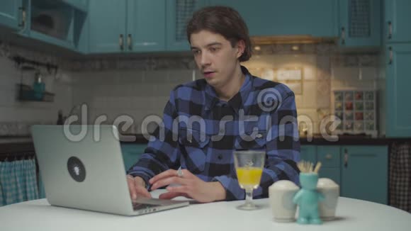 20岁的年轻人在笔记本电脑上读着好消息变得非常兴奋得意洋洋地举起拳头坐在桌子上视频的预览图
