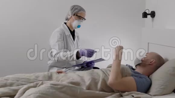 带防护呼吸器的医生正在检查男性流感病人检查体温视频的预览图
