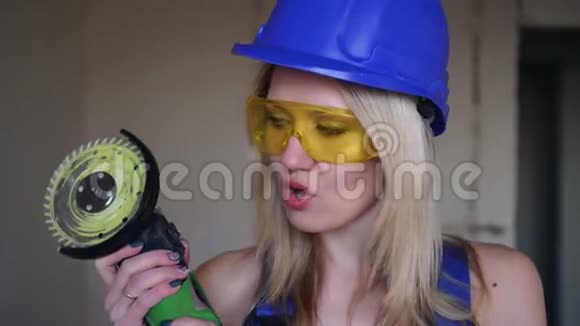 性感的金发女建筑工人与角磨机一个漂亮的建筑女孩的肖像视频的预览图
