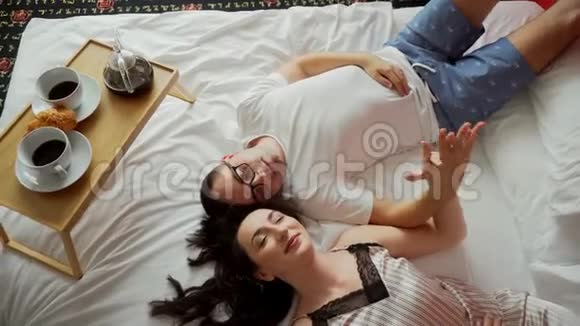 浪漫的情侣躺在床上牵着手早上吃早餐视频的预览图