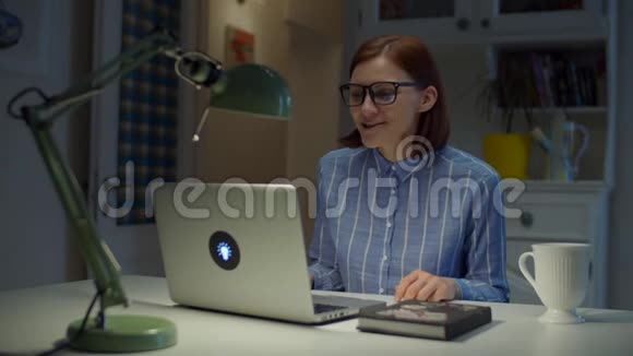 30多岁的年轻女教师戴着眼镜情绪激动地用拇指向上看着家里的笔记本电脑在线教育视频的预览图