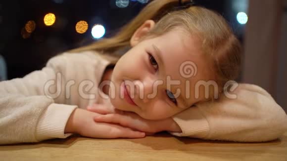 小女孩趴在桌子上看着相机视频的预览图