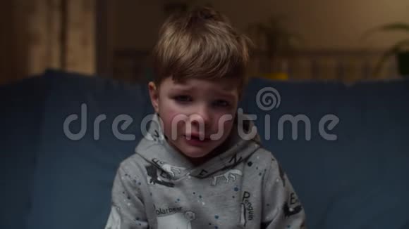 坐在家里的沙发上哭的小男孩的肖像非常沮丧的孩子他的脸看着相机慢动作视频的预览图