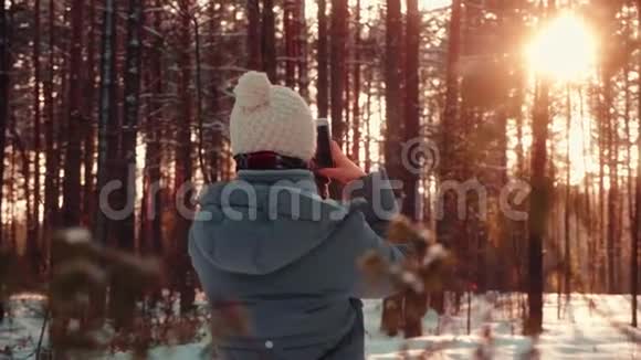 冬季日落林中使用手机的年轻美女画像视频的预览图
