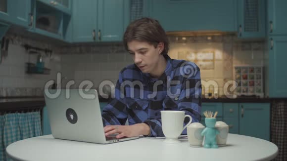 20多岁的年轻人匆匆忙忙地看着笔记本电脑喝了最后一口茶离开了蓝色的厨房男学生视频的预览图